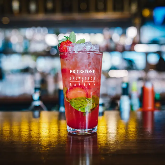 A red berry cocktail garnished with mint on the bar