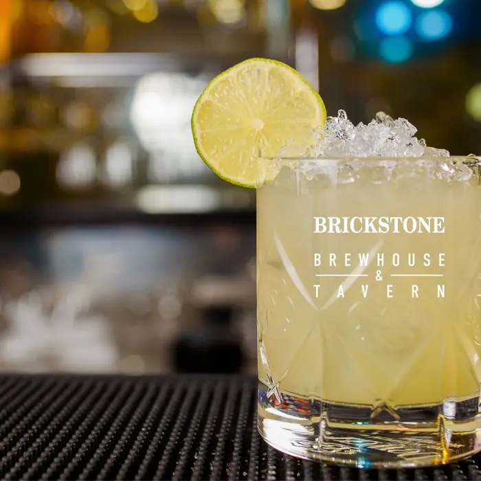 A lemon cocktail on ice with a lime wheel