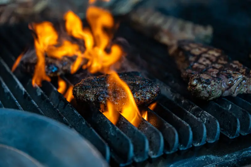 Wagyu burgers and steak over open flame on the grill