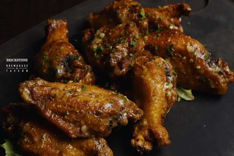 Sauced Brickstone wings on a slate board